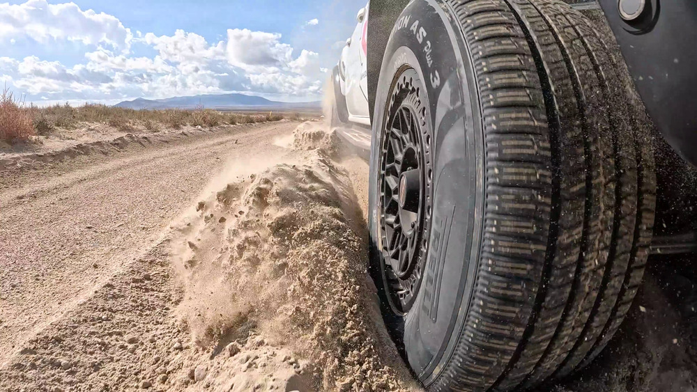 Bir Ford Ranger Raptor'ın yanında gevşek kum savuran Pirelli Scorpion AS Plus 3 lastiği